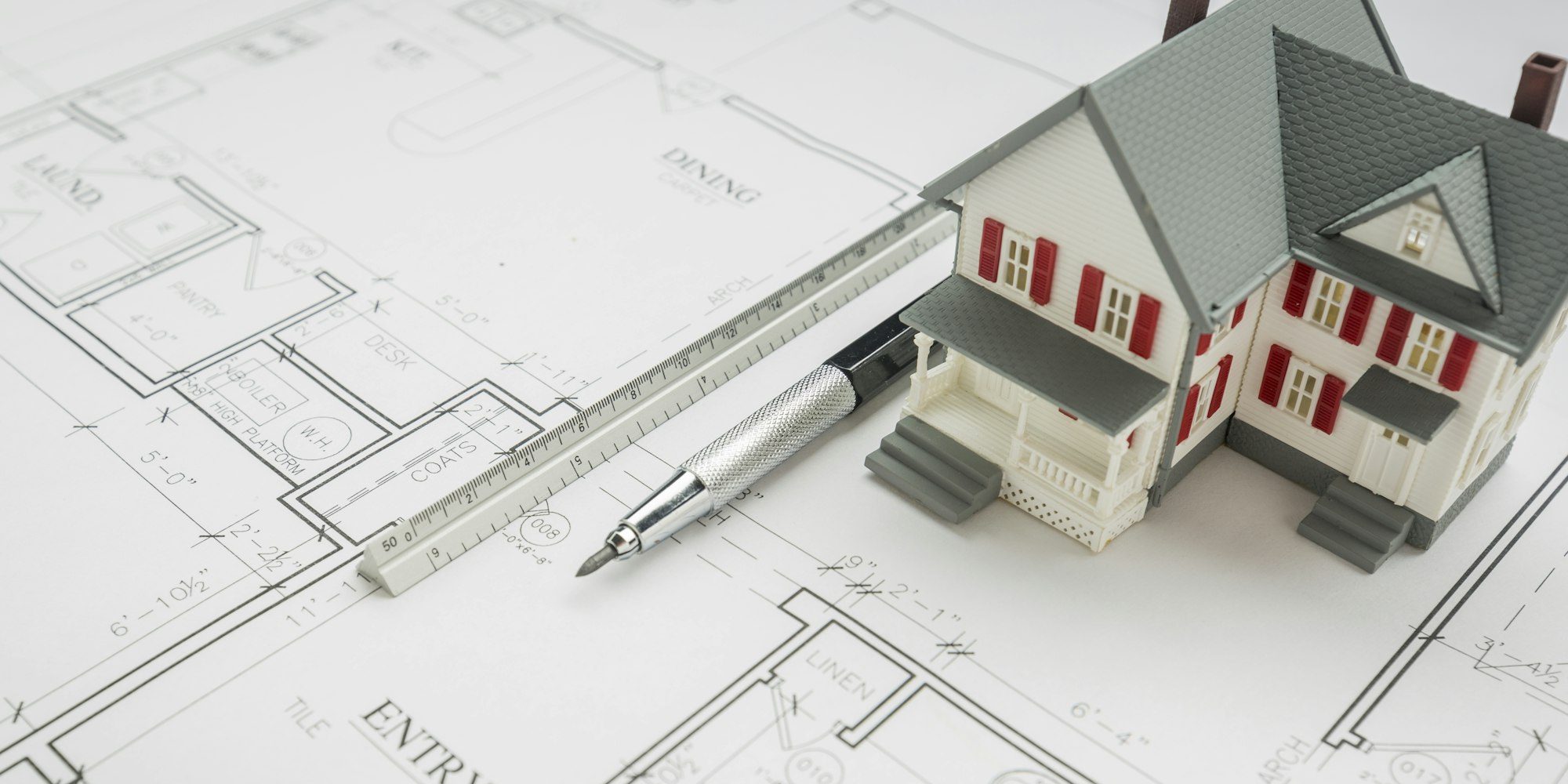 Model Home, Engineer Pencil and Ruler Resting On Custom House Plans.