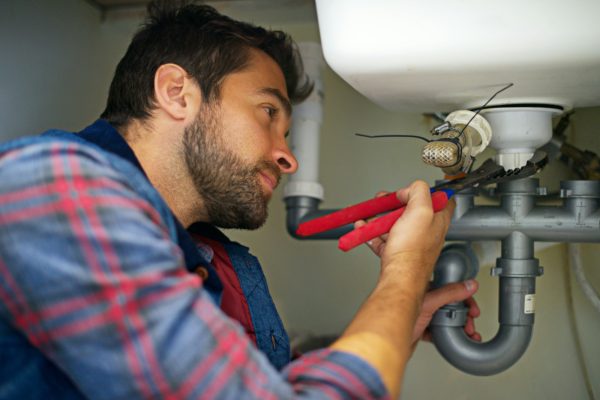 Hes a pro at plumbing. Shot of a plumber fixing a pipe.